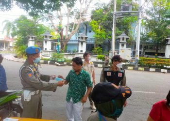 petugas Satpol PP memberikan masker kepada warga yang abai prokes