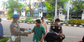 petugas Satpol PP memberikan masker kepada warga yang abai prokes